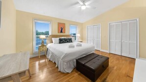 A bedroom with a bed, bedside tables, a bench, a ceiling fan, and closets. - Bid-A-Wee Beach Home-Private Pool (Panama City Beach)