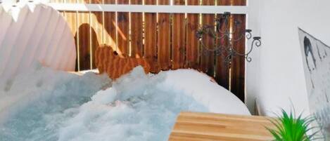 Un jacuzzi con una mesa de madera y una planta en maceta cerca.