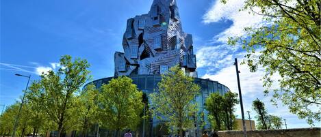 Un bâtiment moderne doté d’une architecture originale, entouré d’arbres et surplombé d’un ciel dégagé.