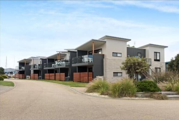Un immeuble résidentiel moderne doté de nombreux balcons et d’une allée pavée.