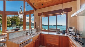 Een moderne keuken met houten kastjes, een inbouwvaatwasser en uitzicht op zee.