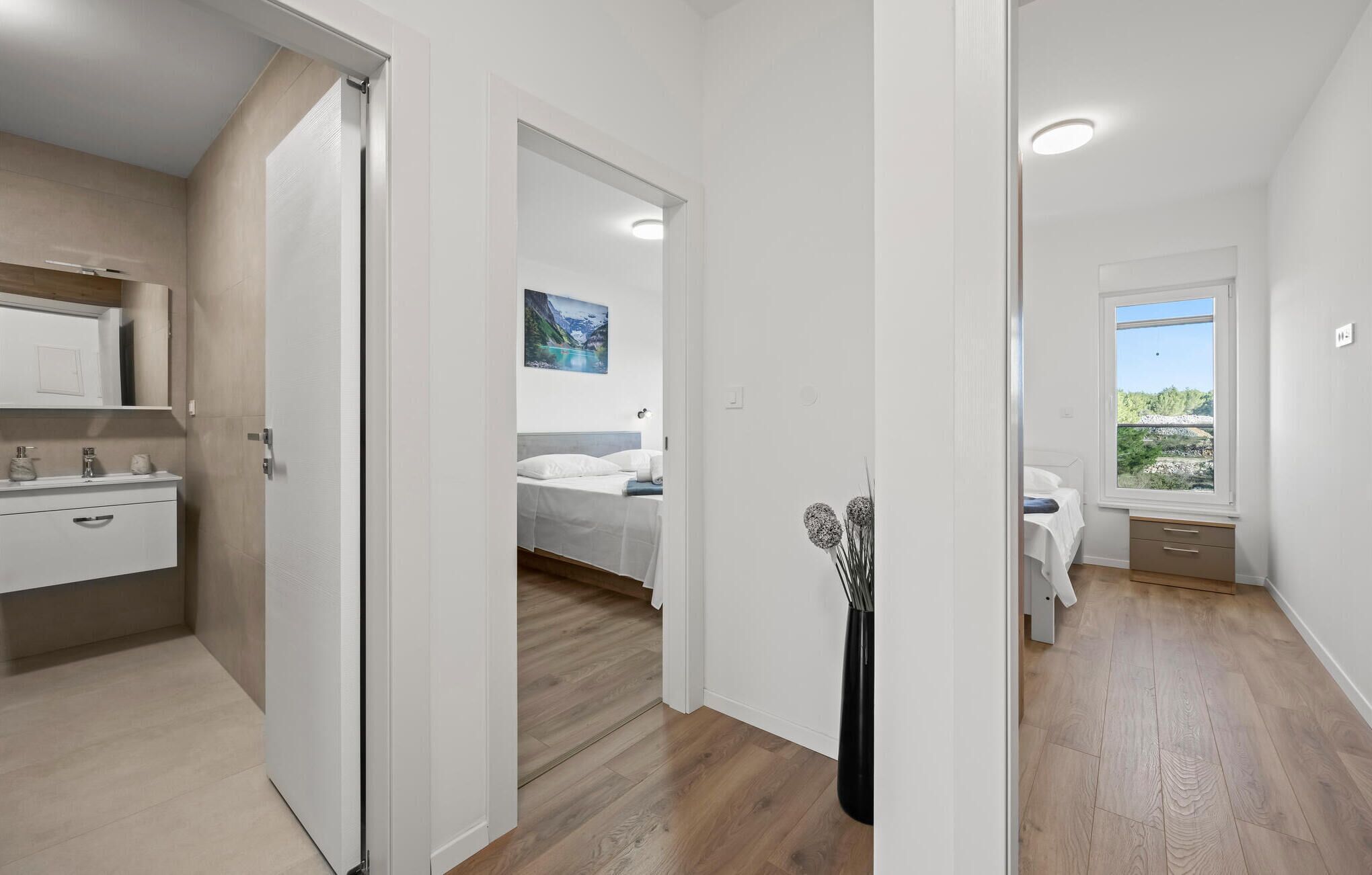 Una camera da letto moderna con un letto, un comodino e una finestra vista verde.