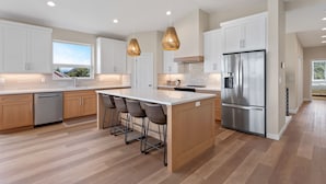 Una cocina moderna con una isla grande, electrodomésticos de acero inoxidable e iluminación colgante.