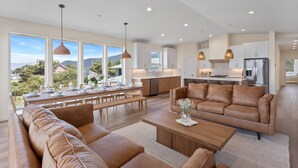 Un salón amplio con un sofá grande, una mesa de comedor preparada para seis personas y una cocina al fondo.