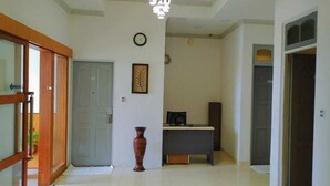 A hallway with a door, a clock, a framed picture, a small table, and a vase. - Turtle Inn Dharavandhoo (Dharavandhoo)