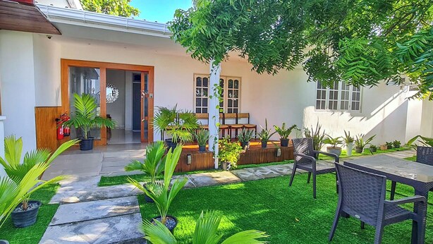 A modern house with a patio area featuring outdoor furniture, a fire extinguisher, and various potted plants. - Turtle Inn Dharavandhoo (Dharavandhoo)