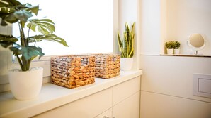 Un baño con tocador blanco, dos cestas tejidas, una planta en maceta y un espejo en la pared.