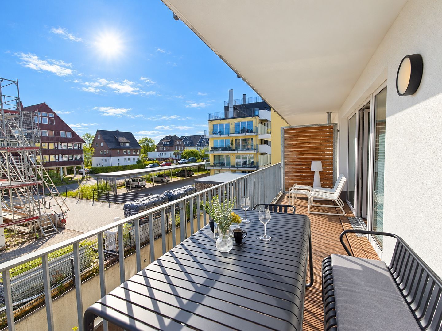 Un balcon avec une table, des chaises et une vue sur les bâtiments environnants.