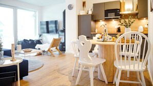 Una cocina moderna con una isla central, sillas blancas y una mesa de comedor.