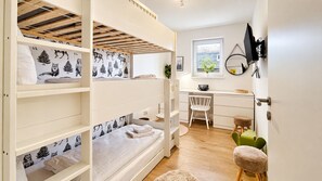 Une chambre avec un lit superposé, un bureau et une chaise, une fenêtre avec vue et un miroir au mur.