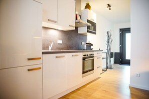 Una cocina moderna con armarios blancos, horno empotrado y microondas.