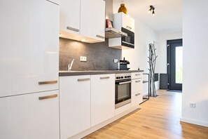 Een moderne keuken met witte kasten, een inbouwoven en een magnetron.