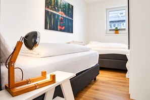 A bedroom with a bed, a desk with a lamp, and a painting on the wall. - Moderne Ferienwohnung im Stadtzentrum: 3 Zimmer, Südbalkon und Infrarotkabine für Max. 4 Personen - (Winterberg)