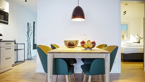 A modern dining area with a wooden table, teal chairs, and a fruit bowl. - Moderne Ferienwohnung im Stadtzentrum: 3 Zimmer, Südbalkon und Infrarotkabine für Max. 4 Personen - (Winterberg)