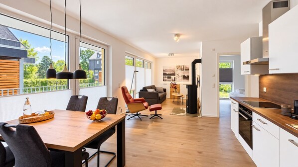 A modern kitchen with a dining area, large windows, and a view of the outdoors.