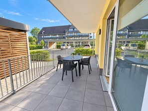 Un balcon avec une table et des chaises, une clôture en bois et une vue sur des immeubles d’habitation.