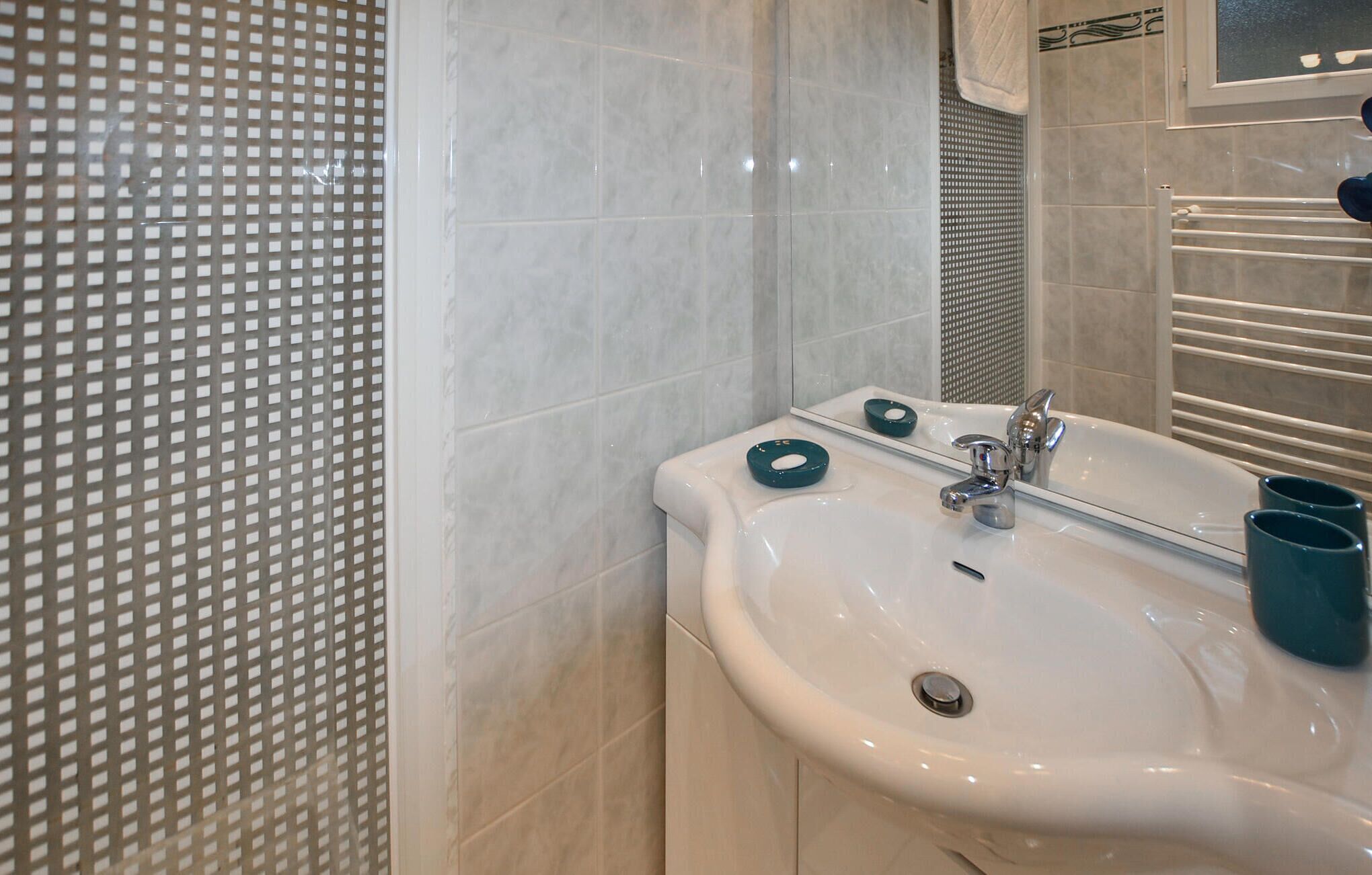 A bathroom with a white sink, a mirror, and a patterned wall.