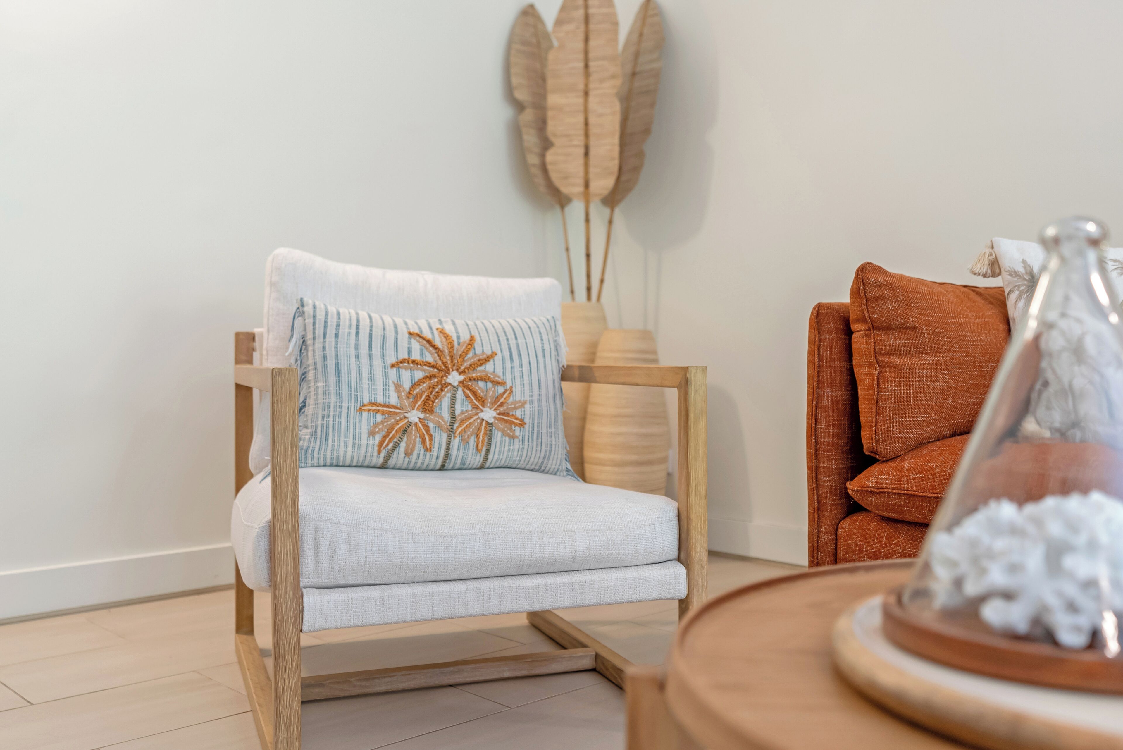 A modern living room with a wooden-framed armchair, a side table with a decorative item, and a wall-mounted decorative piece.