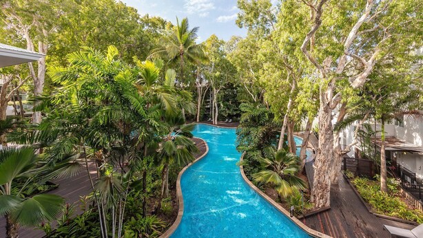 Una piscina rodeada de exuberante vegetación y árboles, con agua cristalina de color azul.