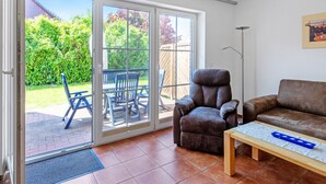 A living room with a sliding glass door leading to a patio with outdoor furniture. - Haus 99 - Seepark Burhave by Interhome (Burhave)