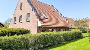 A modern brick building with a sloped roof, multiple windows, and a well-maintained garden. - Haus 99 - Seepark Burhave by Interhome (Burhave)