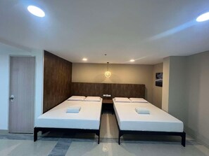 Une chambre d’hôtel avec deux lits, un mur décoratif en bois, un luminaire au plafond et une porte.