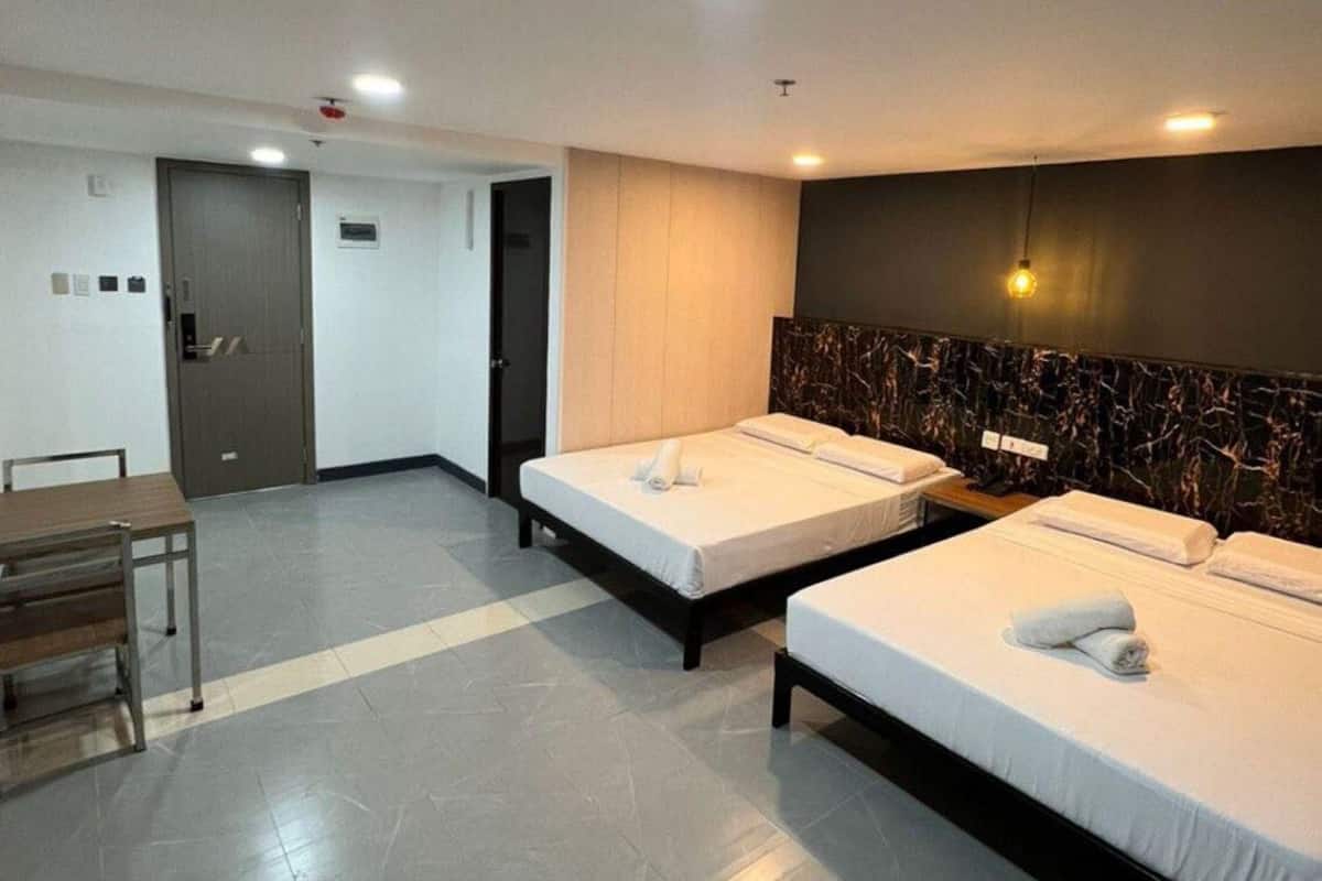 Een hotelkamer met twee eenpersoonsbedden, een bureau en een stoel.