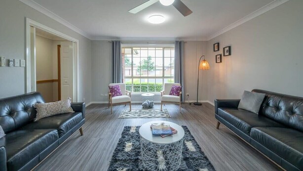 A living room with two black leather sofas, a coffee table, and a ceiling fan. - Windsor. Backyard Entertainer. Dubbo. (Dubbo)