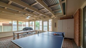A spacious room with a ping pong table, a barbecue grill outside, and large windows allowing natural light. - Windsor. Backyard Entertainer. Dubbo. (Dubbo)