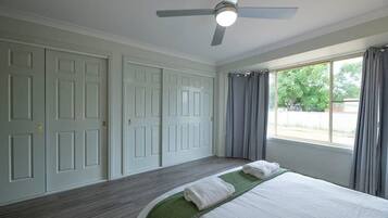 A bedroom with a bed, a ceiling fan, and a window with curtains.
