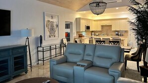 Ein modernes Wohnzimmer mit einem grauen Sofa, einem Couchtisch und einer Chandelieber.