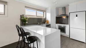 Una cocina moderna con una isla central, armarios blancos y una campana extractora de acero inoxidable.