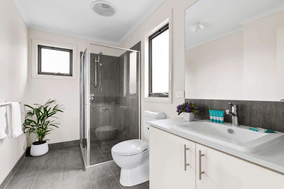 Ein modernes Badezimmer mit Dusche, Toilette, Waschbecken und einem Blumentopf.