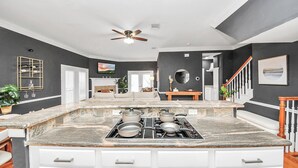 Una cocina moderna con una isla central, armarios blancos y un ventilador de techo.