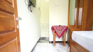 A hotel room with a wooden wardrobe, a bed with a white mattress, a marble floor, and a small table with a red tablecloth. - OYO Life 93382 Gajayana Kost Female Only Syariah (Malang)