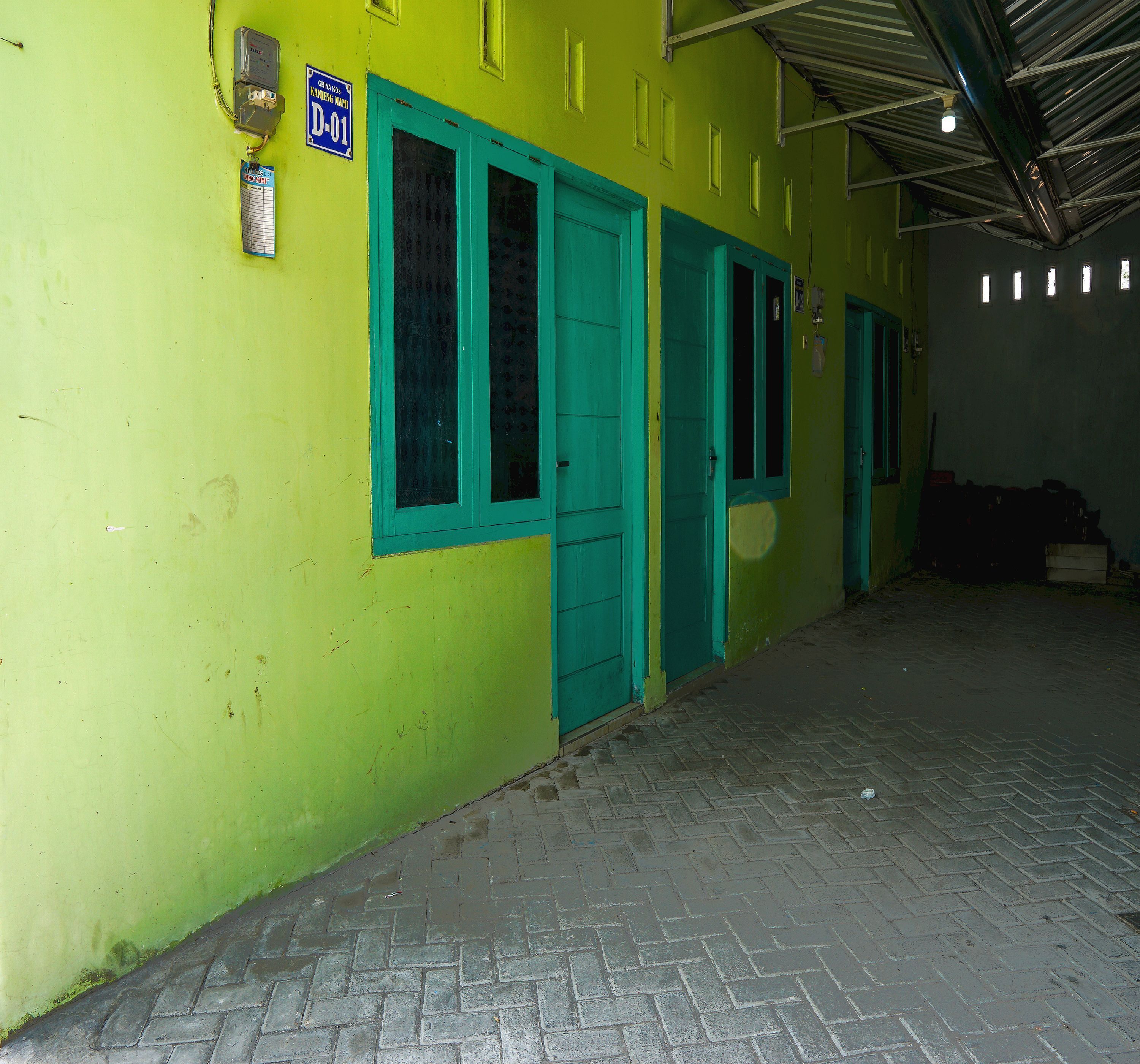 A building with a bright yellow exterior, teal doors, and a sign indicating a specific room number.