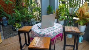 A wooden table with a laptop, surrounded by potted plants and a patterned tablecloth. - OYO Life 93382 Gajayana Kost Female Only Syariah (Malang)