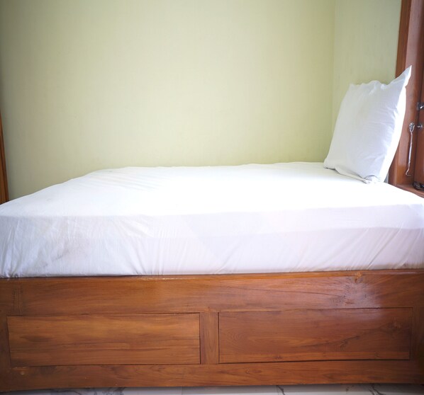A single bed with a wooden frame and a white mattress.