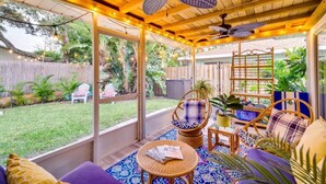 A covered outdoor patio with wooden ceiling and ceiling fans, wicker furniture, and a view of the backyard. - Beachside Cottage - 5 min walk to the Beach (Cocoa Beach)