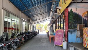 A covered outdoor area with a row of parked motorcycles, a sign for Luna Salon Spa, and a mural on the wall. - Hotel O New Asembagus 3 (Asembagus)