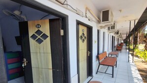 A corridor with doors, a bench, and a tiled floor. - Hotel O New Asembagus 3 (Asembagus)