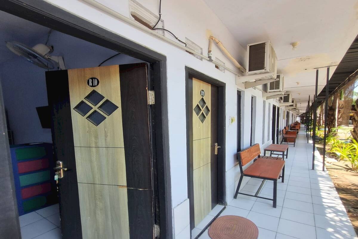 A corridor with doors, a bench, and a tiled floor.