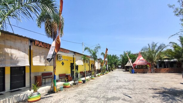A street with buildings, palm trees, and a paved road. - Hotel O New Asembagus 3 (Asembagus)
