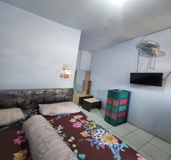 A bedroom with a bed, pillows, a dresser, a mirror, and a TV.