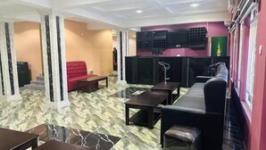 A hotel lobby with a red sofa, black and white marble flooring, and a black sectional sofa. - Davina hill resorts and hotel  (Abuja)