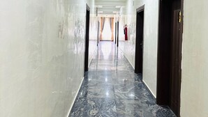 A long, narrow hallway with marble flooring and white walls. - Davina hill resorts and hotel  (Abuja)