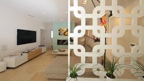 A modern living room with a flat-screen TV, a wooden entertainment unit, a sofa, and a decorative white partition. - Une Villa Luxueuse à Saint Remy de Provence , A 5 Minutes du Centre , au Calme (Saint-Rémy-de-Provence)