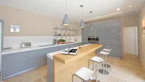 A modern kitchen with a central island, bar stools, pendant lights, and built-in appliances. - Une Villa Luxueuse à Saint Remy de Provence , A 5 Minutes du Centre , au Calme (Saint-Rémy-de-Provence)