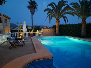 A swimming pool with a white and blue tiled edge, surrounded by palm trees and a white railing.