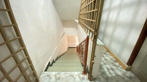 A narrow stairway with a metal railing and a wooden handrail, leading to a landing. - Hotel O California (Batam)